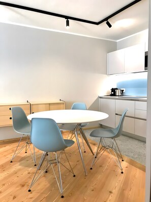 A modern kitchen with white cabinets, a round table, and four blue chairs. - Apartment 'Palazzo Righi - Blu' with Mountain View, Balcony and Wi-Fi (Carisolo)