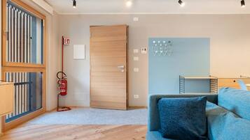 Una habitación moderna con suelo de madera, un sofá azul, una puerta de madera y un extintor.