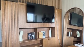 Ein modernes Wohnzimmer mit integriertem Fernseher, Holzvertäfelung und einer kleinen Sitzecke.