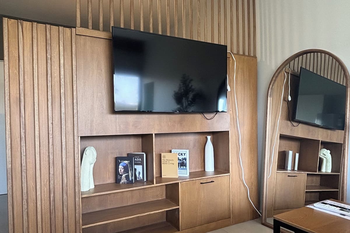 A modern living room with a built-in TV, wooden paneling, and a small seating area.