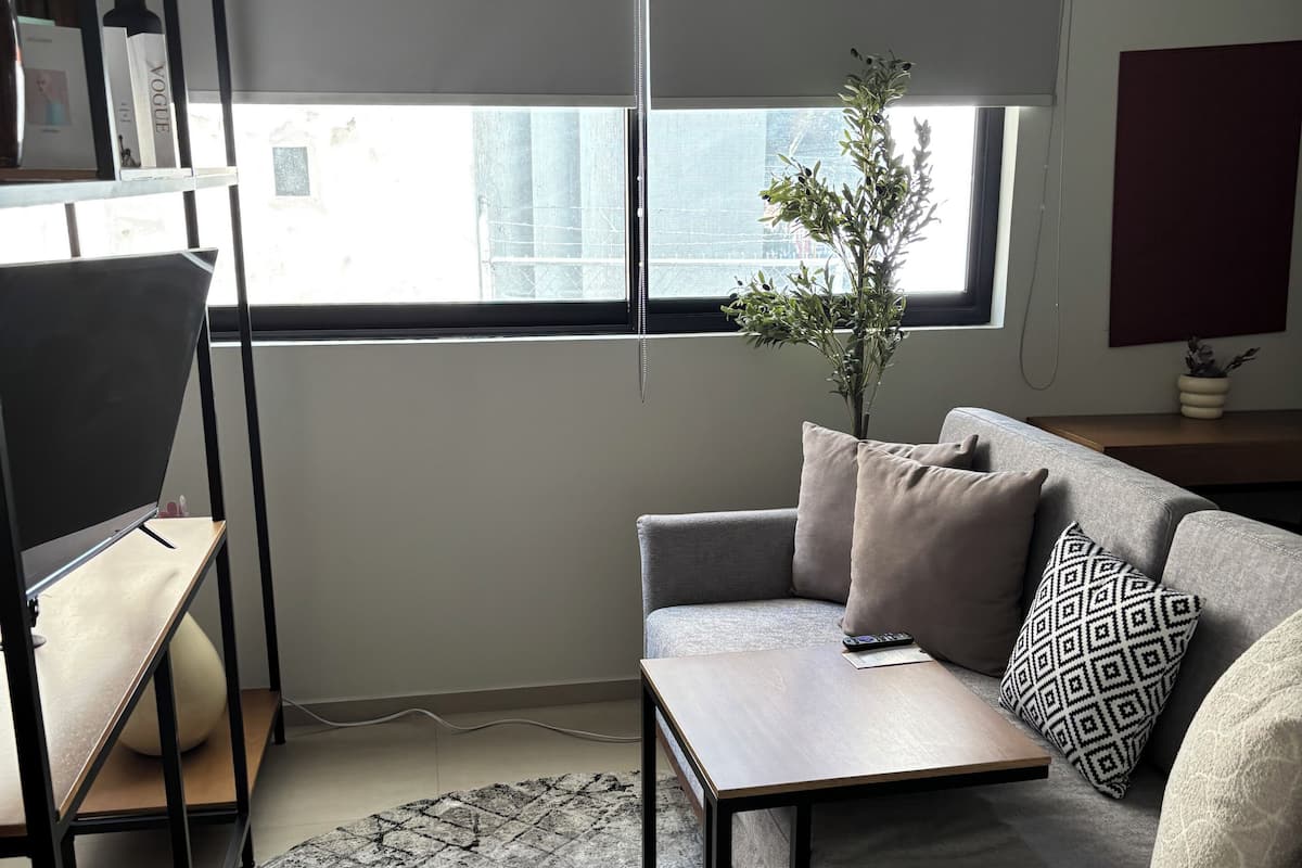 A modern living room with a grey sofa, a small wooden table, and a patterned rug.