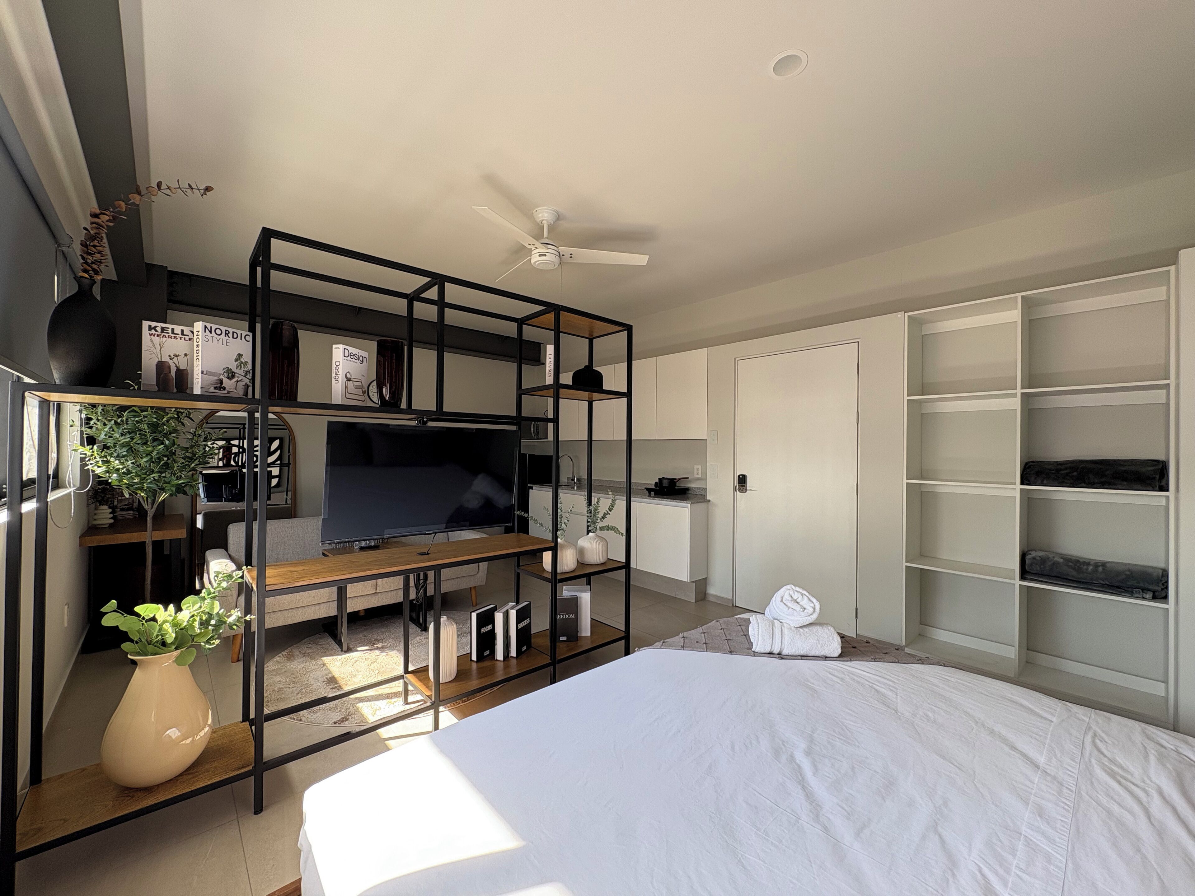 A modern bedroom with a bed, a TV, a desk, and a wardrobe.