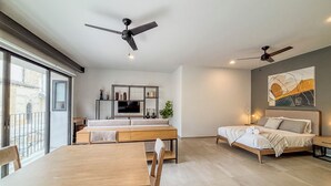 Ein modernes Wohnzimmer mit Essbereich, einer Couch, einem Fernseher und zwei Deckenventilatoren.