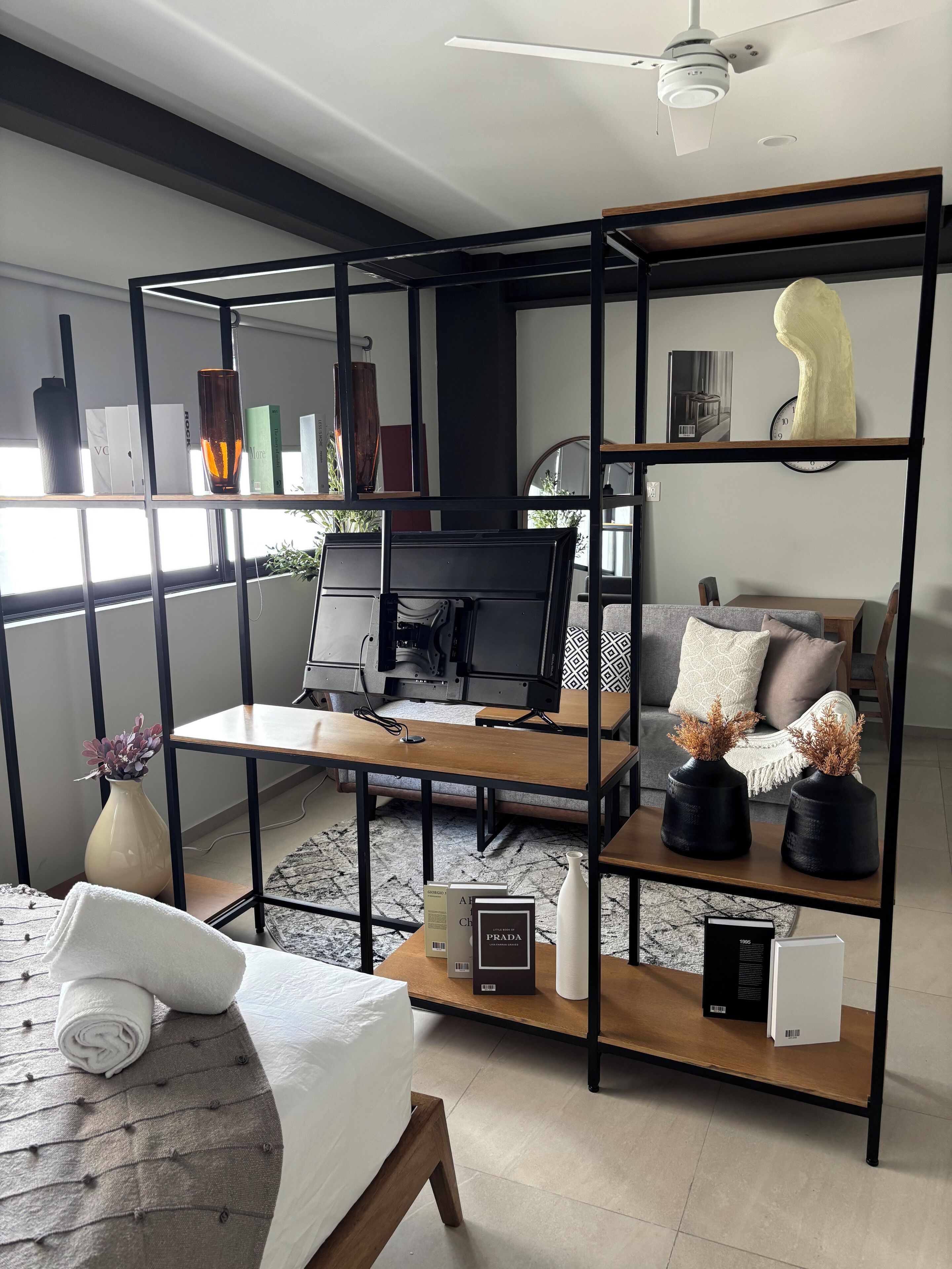 Una sala de estar moderna con una estantería de metal negro, una mesa de centro de madera, un sofá y un televisor.