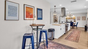 Una cucina moderna con mobili bianchi, un'isola centrale e sgabelli da bar blu.