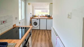 A compact kitchen with a built-in oven, a washing machine, and a small countertop. - 3 bedroom accommodation in Weymouth (Weymouth)