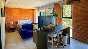 A modern kitchen with a central island, a dining area with stools, a blue sofa, and a brick wall. - Americana apartment with rooftop pool (Guadalajara)