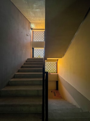 A staircase with a handrail, leading to a landing with a window with a grid pattern. - Americana apartment with rooftop pool (Guadalajara)