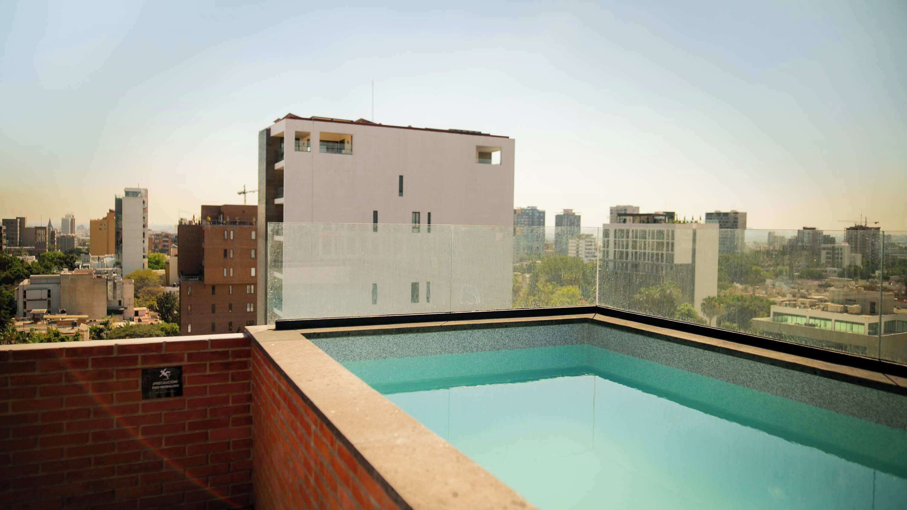 A rooftop pool with a city view, surrounded by buildings.