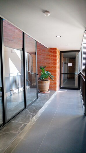 A modern hallway with glass doors, a large potted plant, and a brick wall. - Modern stay in Colonia Americana (Guadalajara)