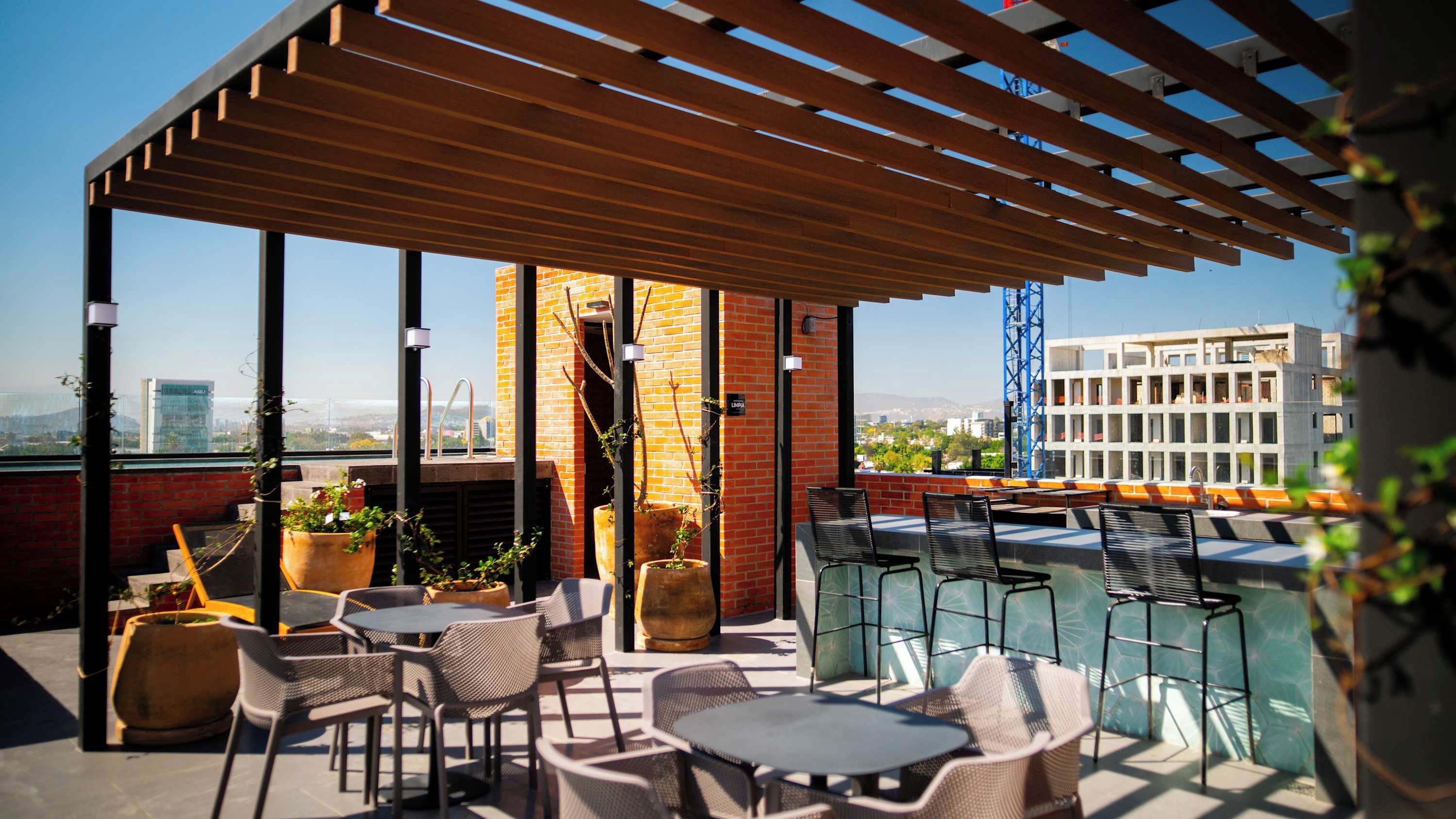A rooftop terrace with outdoor seating, potted plants, and a view of the cityscape.
