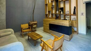 A modern living room with a sofa, wooden chairs, a coffee table, a wooden bookshelf, and a potted plant. - Modern stay in Colonia Americana (Guadalajara)