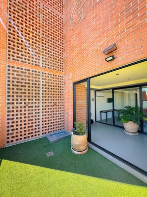 A brick building with a glass door entrance, a small outdoor seating area with a table and chairs, and a potted plant. - Modern stay in Colonia Americana (Guadalajara)