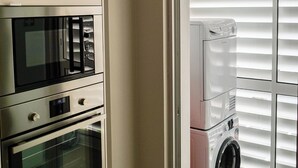 A compact kitchen with a built-in microwave, oven, and a washer-dryer unit. - São Pedro Apartment (Vila Franca Do Campo)
