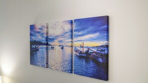 Obra de arte em três painéis retratando um pôr do sol sobre um porto com barcos.