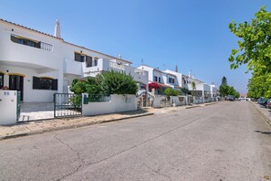 A street with white buildings, a clear sky, and a paved road.