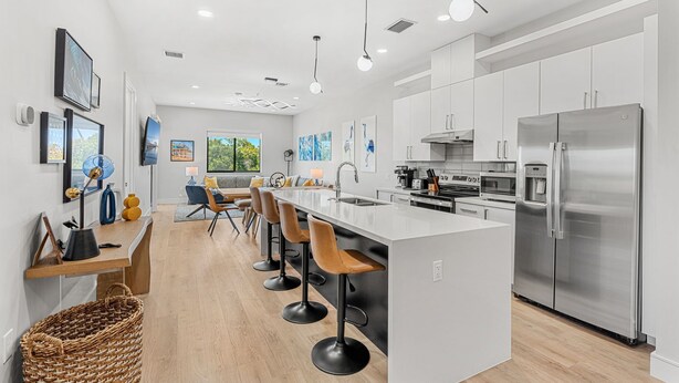 A modern kitchen with a central island, stainless steel appliances, and a dining area with bar stools.