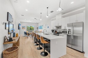 Una cocina moderna con una isla central, electrodomésticos de acero inoxidable y una zona de comedor con taburetes de bar.