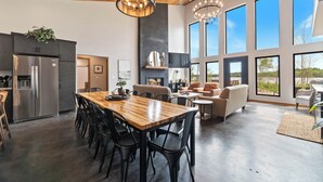 Une cuisine spacieuse dotée d’un grand îlot central, d’appareils électroménagers modernes et de grandes fenêtres offrant une vue sur l’extérieur.
