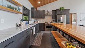 Une cuisine moderne avec des meubles de couleur sombre, un plan de travail en bois et un îlot central.