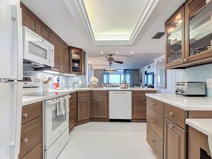 Uma cozinha moderna com armários de madeira, micro-ondas embutido e uma ilha central.