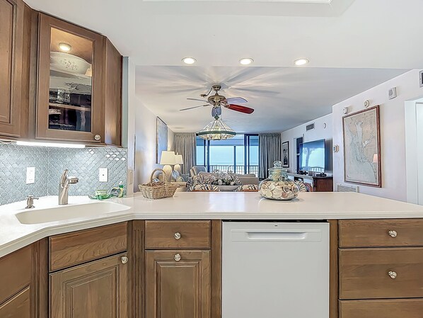 A modern kitchen with wooden cabinets, a white countertop, and a ceiling fan.