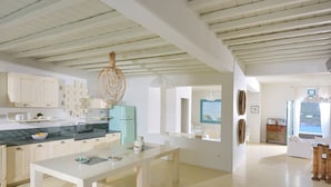 A spacious kitchen with white cabinetry, a marble countertop, and a central island. - Villa Irida (Mikonos)