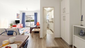Ein modernes Apartment mit Essbereich, Küche und einem Balkon mit blauen Vorhängen.