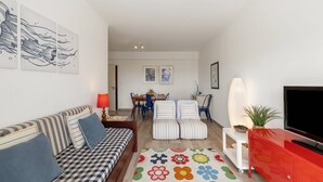 Ein modernes Wohnzimmer mit einer Couch, Sesseln, einem Fernseher und Kunstwerken an den Wänden.