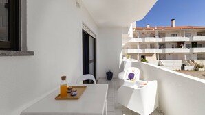 Ein Balkon mit einem weißen Tisch, einer Flasche und einer Etagere mit Gebäck.