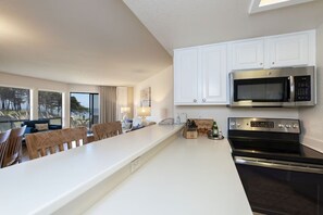 A modern kitchen with white cabinetry, a built-in microwave, and a stove.