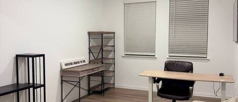 A modern, minimalistic living room with a wooden coffee table, a sofa, a desk with a chair, and built-in shelving.