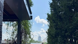 Ein überdachter Außenbereich mit einer Steinsitzbank, Topfpflanzen und Blick auf eine Stadtlandschaft.