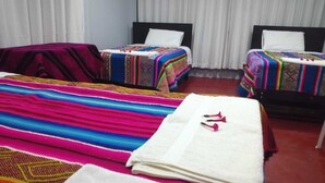 A hotel room with two beds, each with colorful bedding and pillows.