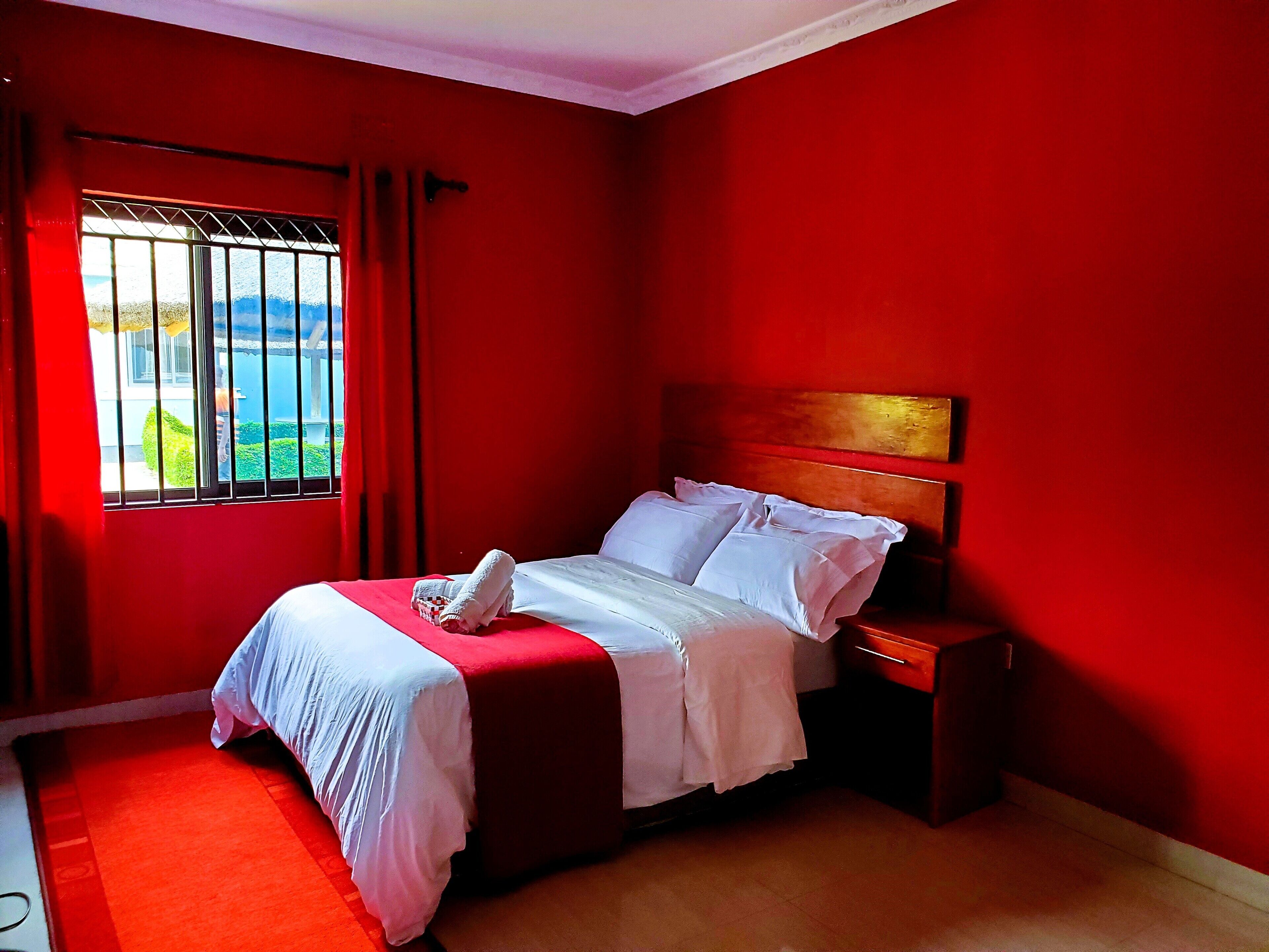 A room with a bed, a nightstand, and a window with curtains.