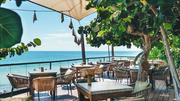 Un espace extérieur aménagé avec des tables et des chaises, offrant une vue sur la mer.