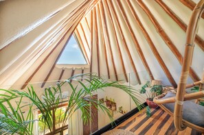 A cozy, triangular room with a sloped ceiling, a small skylight, and a wooden chair. - Mezzanine by La Zebra, an SLH Hotel (Tulum)