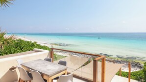 Une terrasse avec une table et des chaises donnant sur une plage.