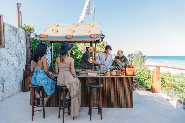 A bar area with stools and a wooden counter, overlooking a beach. - Mezzanine by La Zebra, an SLH Hotel (Tulum)