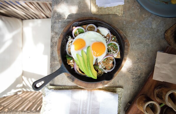 En pande med æg, avocado og løg på et bord.
