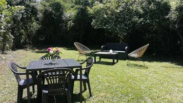 Un espacio al aire libre con mesa y sillas, un sofá y una silla de descanso.