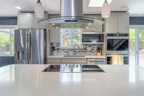 Cocina moderna con electrodomésticos de acero inoxidable, una isla central y un amplio ventanal que proporciona luz natural.