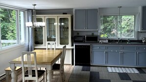 Eine moderne Küche mit Esstisch aus Holz, weißen Stühlen und grauen Schränken.