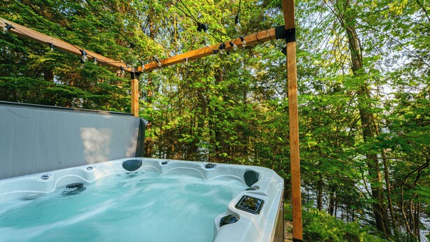 Ein Whirlpool in einer bewaldeten Gegend, überdacht mit einer Holzpergola.