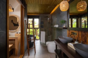Une salle de bain moderne avec un grand miroir, deux lavabos, une douche et un porte-serviettes en forme d’échelle.