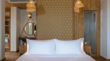 A neatly made bed with white linens, two bedside lamps, a bedside table, a mirror, and a patterned wall.