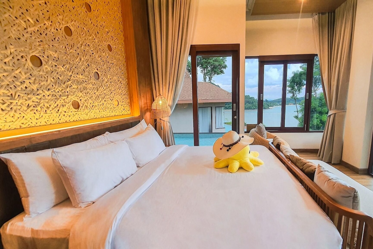 Een hotelkamer met een groot bed, een decoratieve wand en uitzicht op een waterpartij.