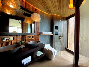 Une salle de bain moderne avec deux lavabos, un grand miroir et une douche à l’italienne.