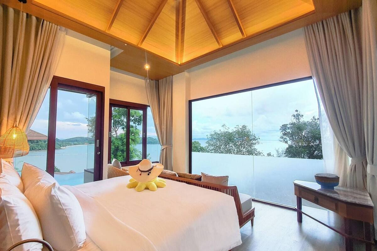 Een slaapkamer met een groot bed, uitzicht op zee en een balkon.