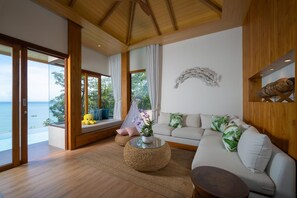 A modern living room with a view of the sea, a sofa, a coffee table, and a decorative wall piece. - Sinae Phuket Luxury Hotel (Ratsada)